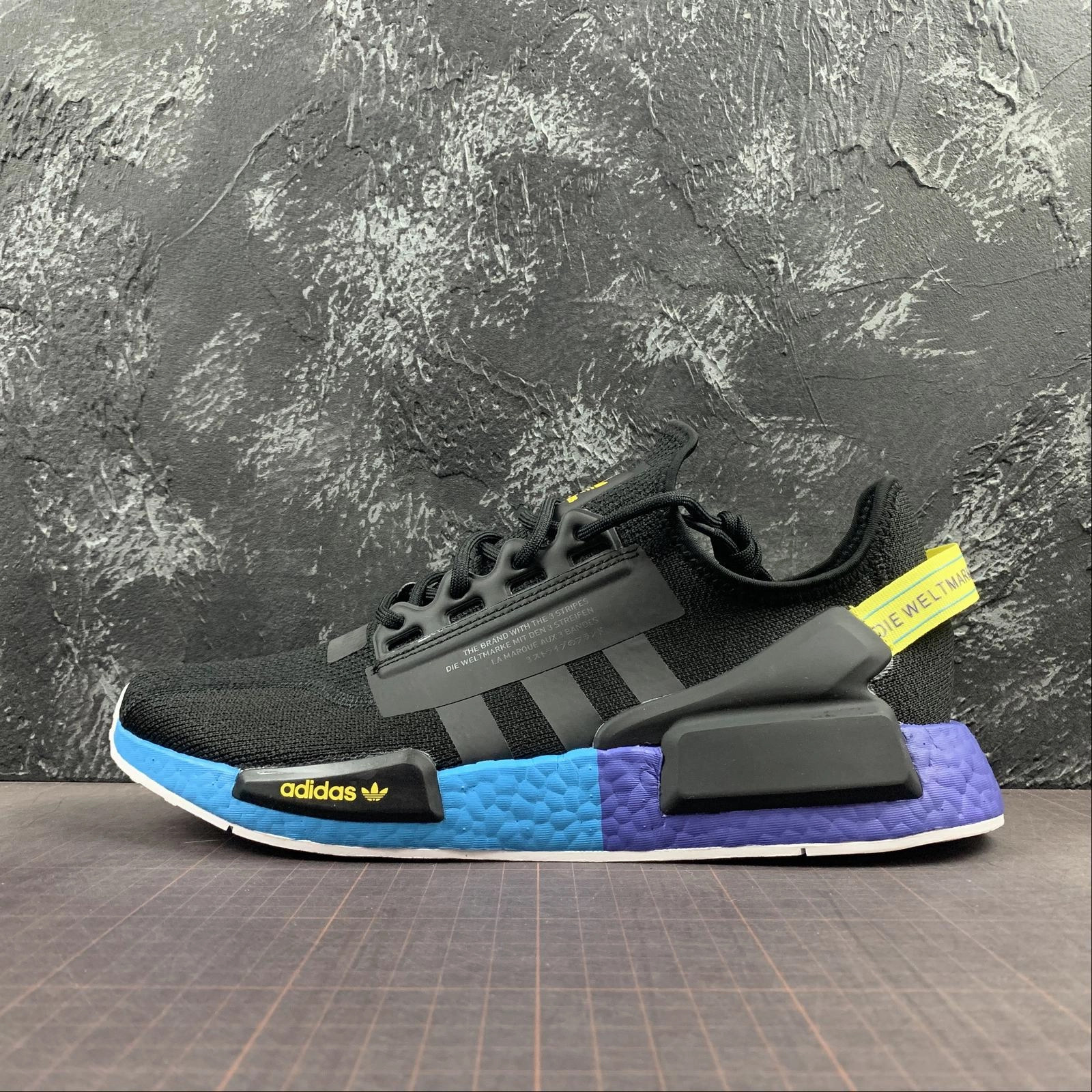 Adidas NMD R1 V2 Black Carbon Shock Yellow running in a stone bridge area shoes