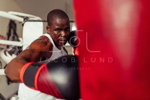 Boxer striking a red punching bag with a gloved fist