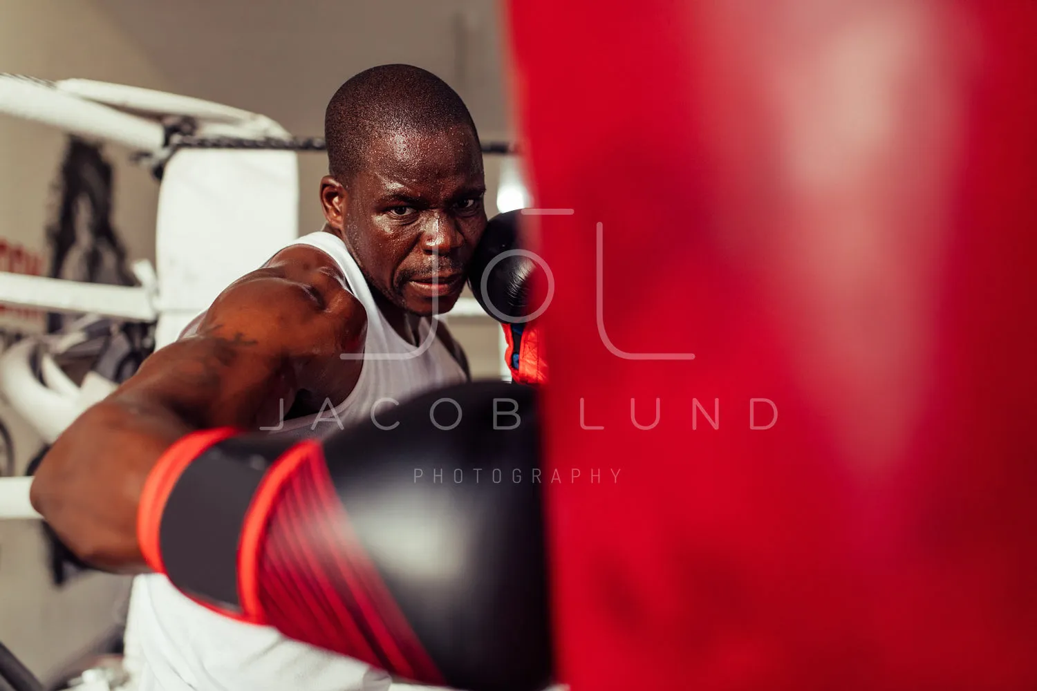 Boxer striking a red punching bag with a gloved fist